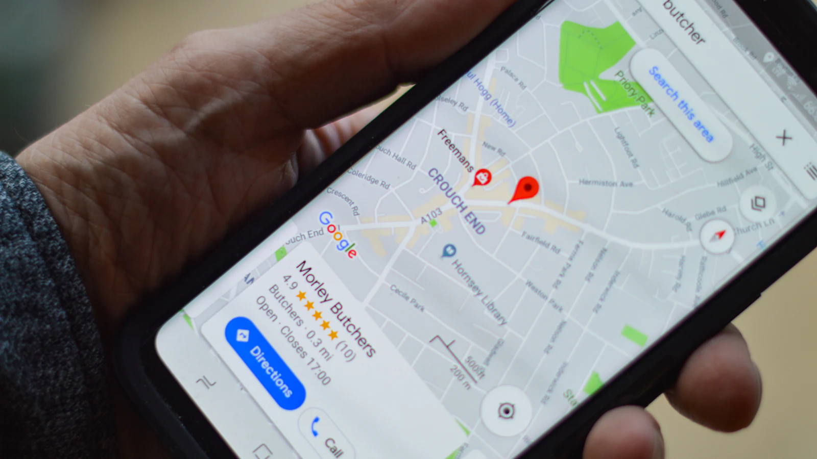 Person sucht auf dem Smartphone in Google Maps nach einem Geschäft in der Nähe